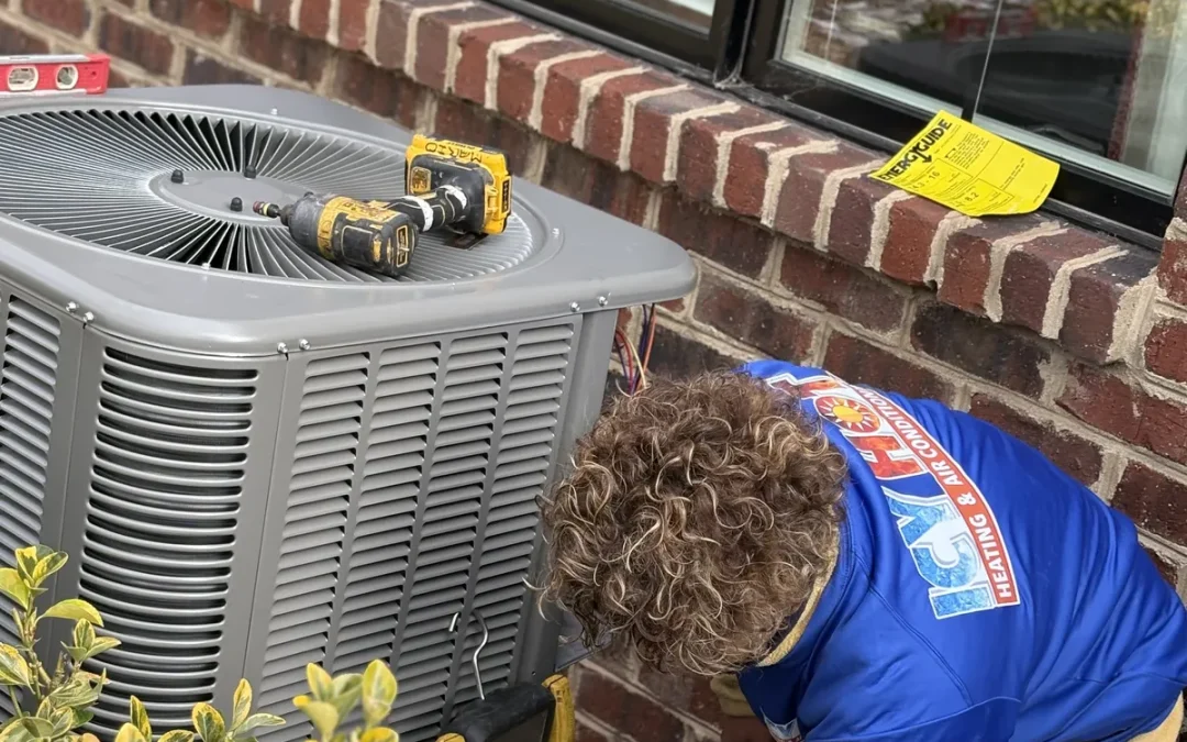 Icy Hot Heating and Air Conditioning technician installing an outdoor AC condenser unit beside a brick home