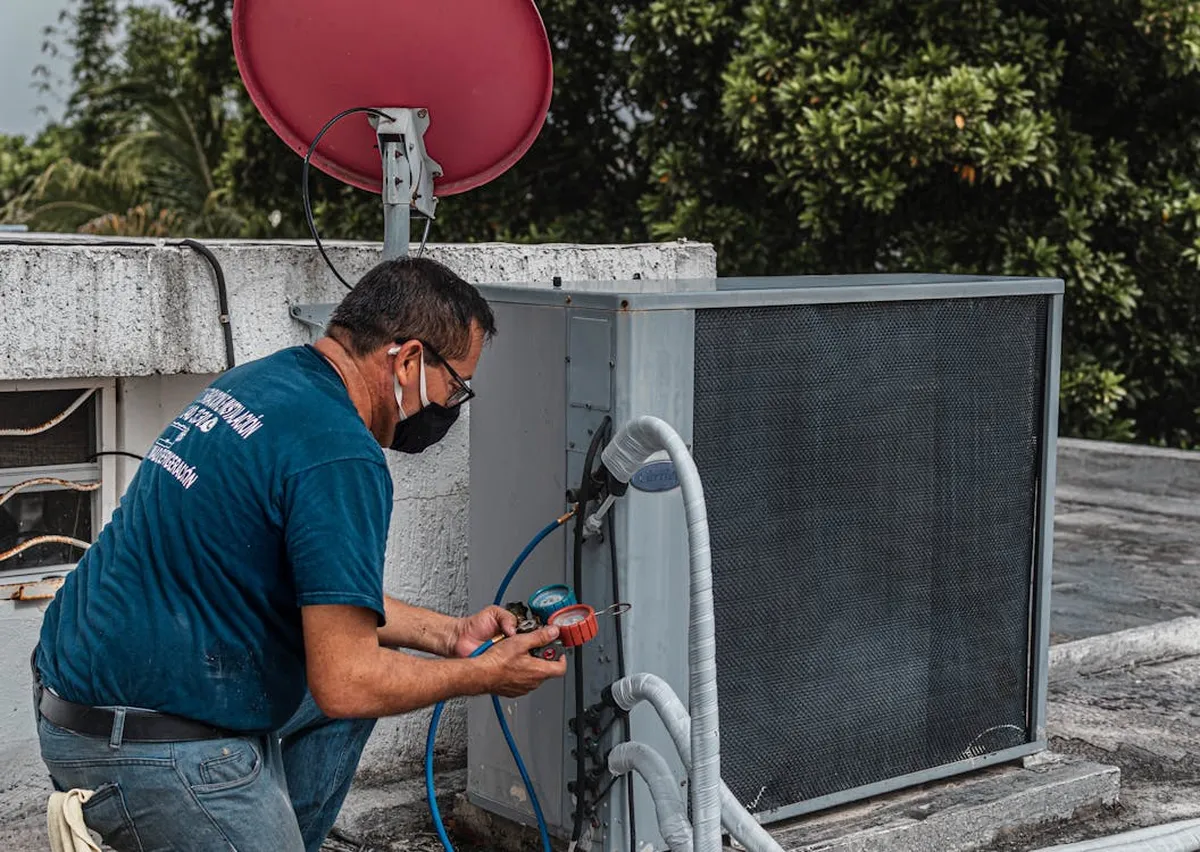 HVAC technician using manifold gauges to diagnose an outdoor air conditioning unit