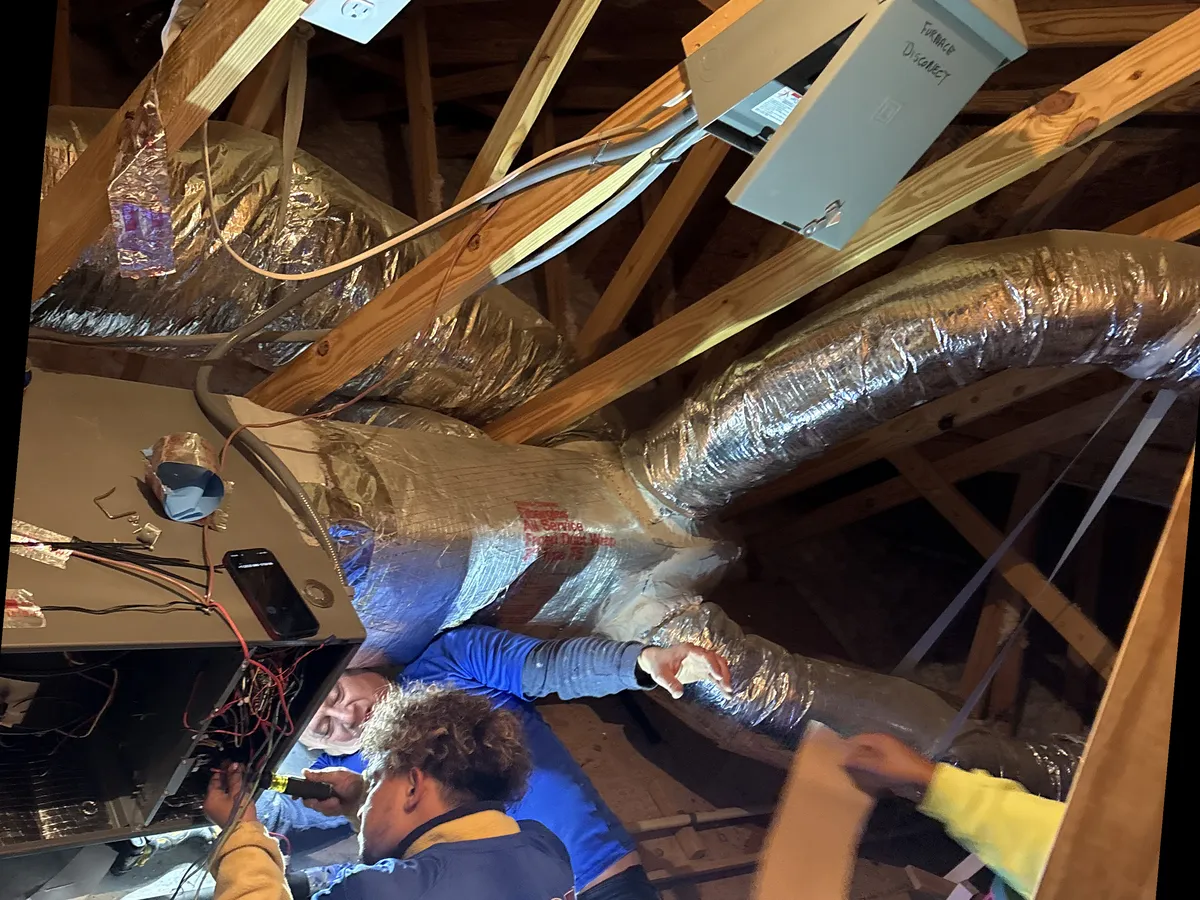 Icy Hot Heating and Air Conditioning technician installing an HVAC air handler and ductwork in a residential attic