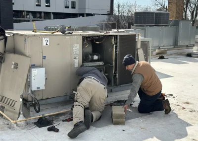 Two HVAC technicians performing maintenance on commercial rooftop unit