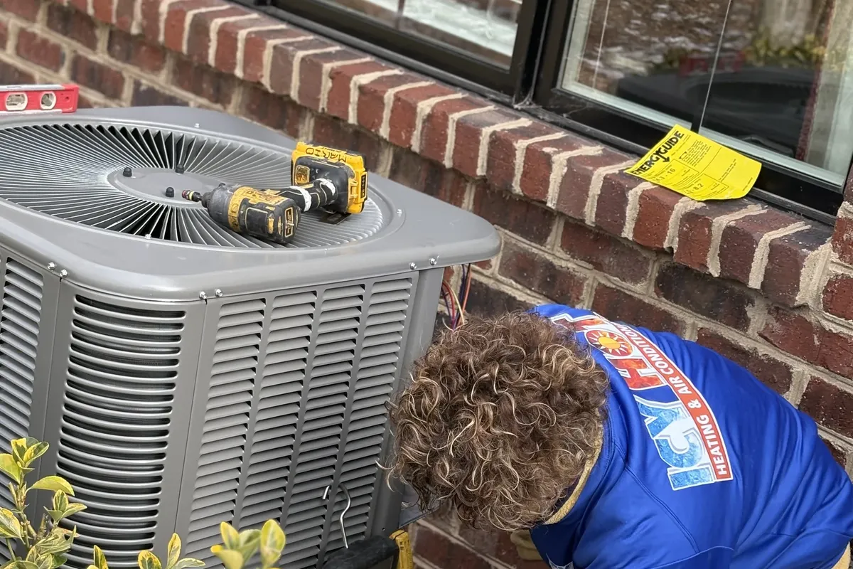 HVAC technician servicing an outdoor air conditioning unit in a residential yard
