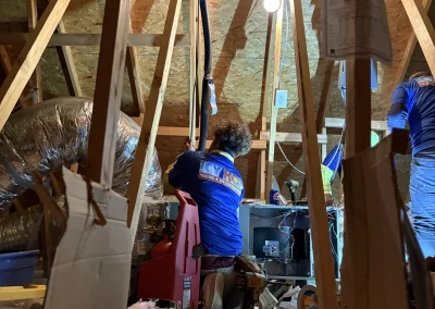 Icy Hot technician in blue uniform servicing HVAC equipment in attic space