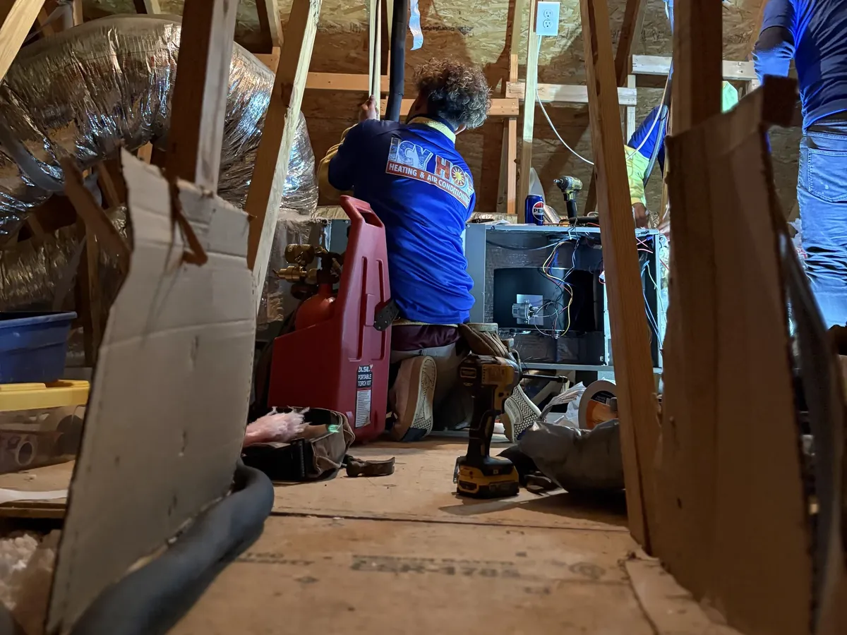 Icy Hot HVAC technician performing a spring tune-up inspection on an attic air handling unit in a Raleigh home