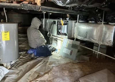 HVAC technician performing furnace maintenance in residential crawl space