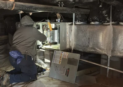 HVAC technician servicing heating system and ductwork in crawl space
