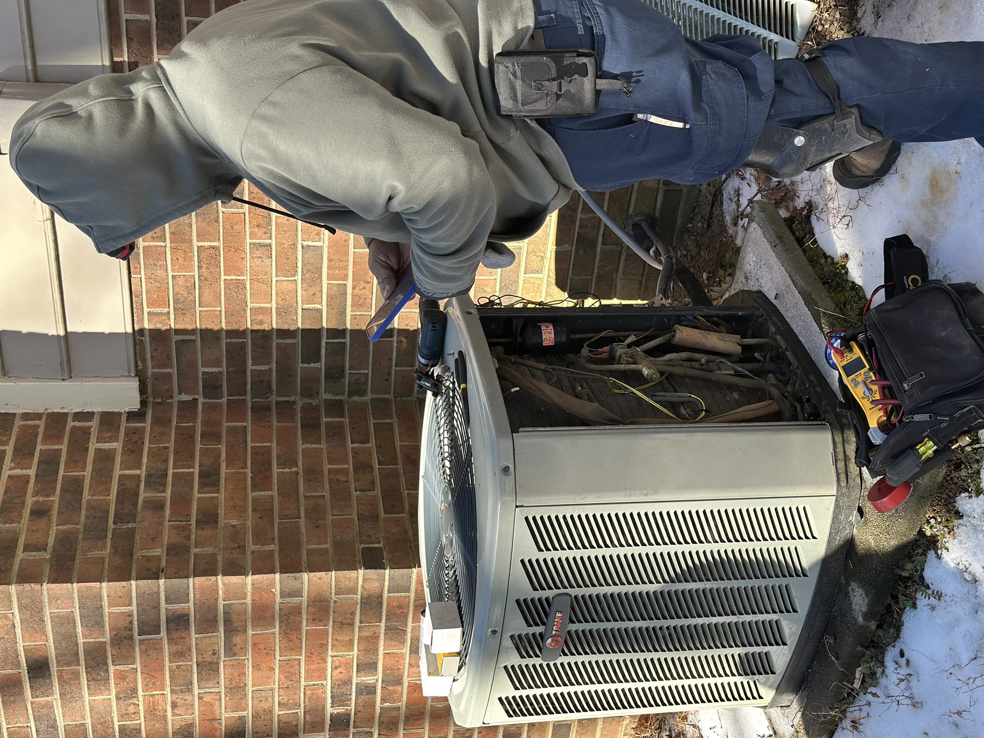 Icy Hot Heating and Air Conditioning technician servicing a residential heat pump in Raleigh, NC during winter
