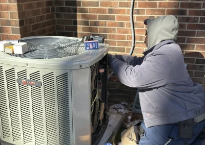 HVAC technician working on Trane outdoor air conditioning unit beside brick building