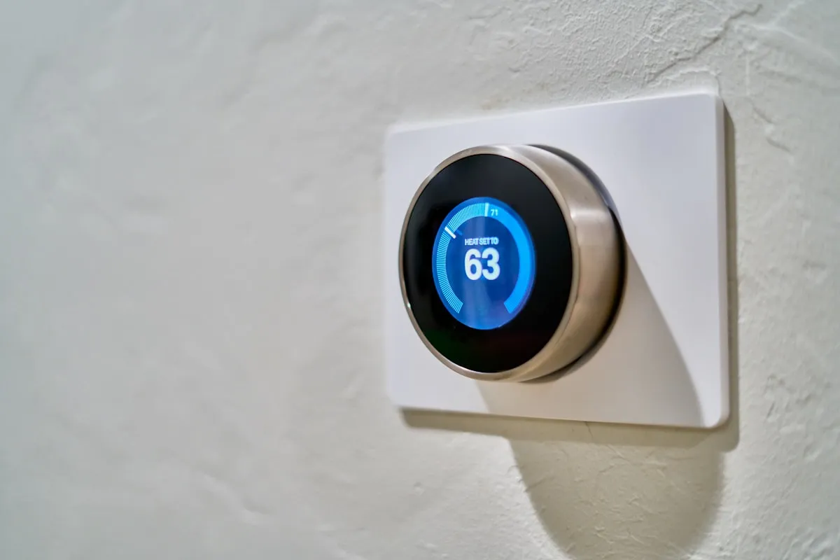 Nest smart thermostat mounted on wall displaying temperature setting for home heating